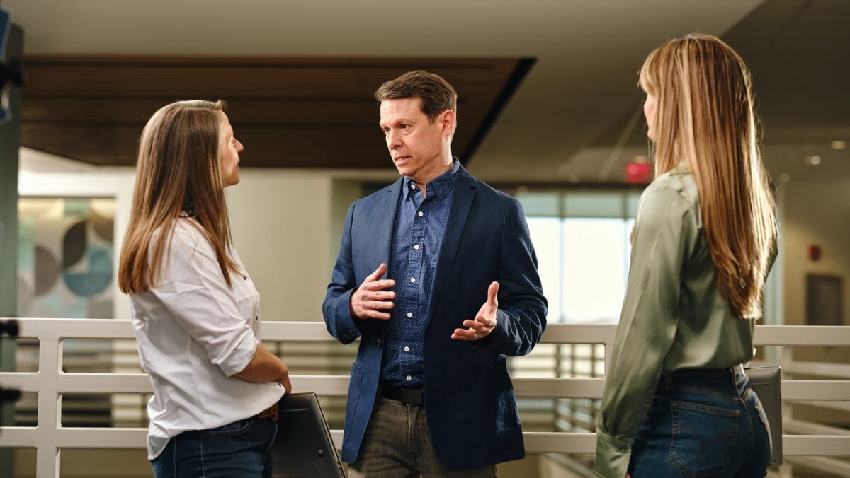 three adults interacting on college campus